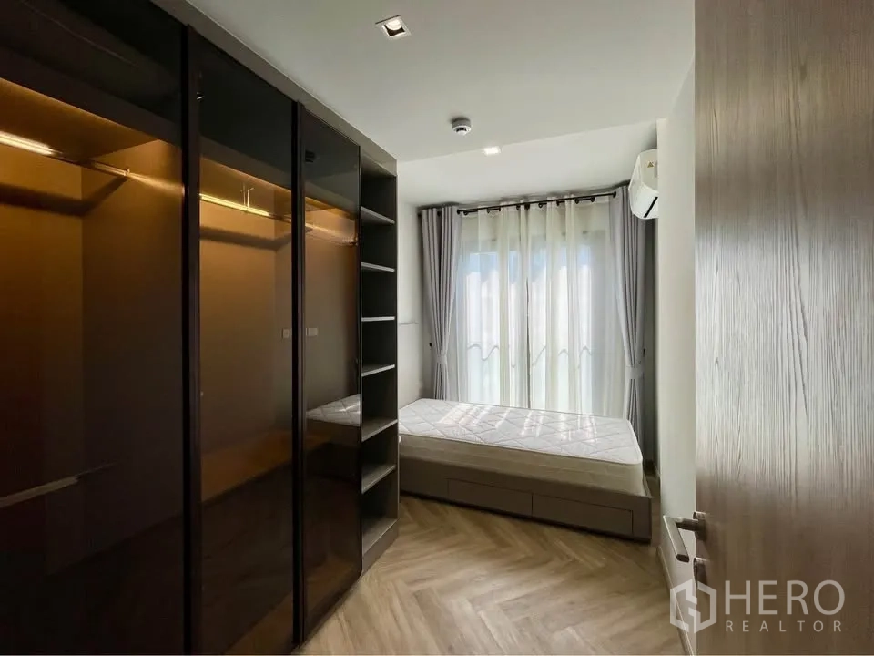คอนโด for rent in Watthana, Bangkok - ห้องนอนมีตู้เสื้อผ้าบานกระจก เตียง ผ้าม่านโปร่ง และพื้นลายก้างปลาไม้