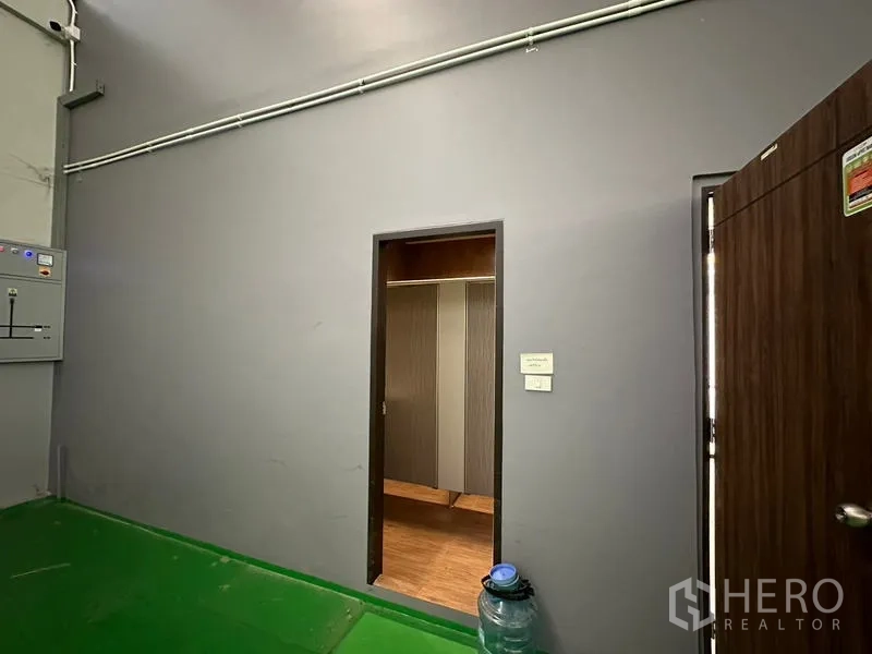 工厂 出租或出售在Lam Luk Ka, Pathum Thani - 仓库墙面通往洗手间或更衣室的门，旁有电控面板。