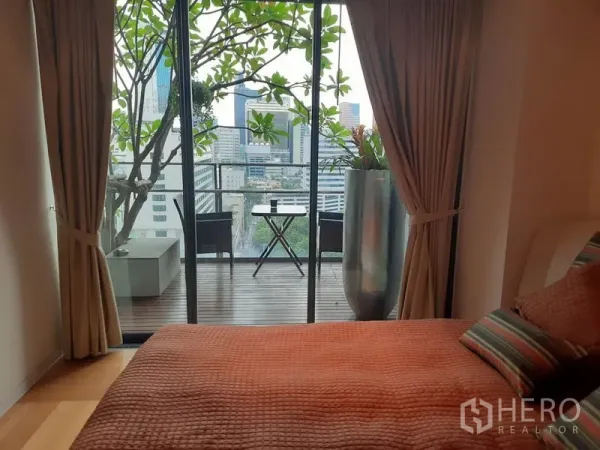 คอนโด ให้เช่าหรือขายในSathon, Bangkok - ห้องนอนเปิดสู่ระเบียงด้วยประตูกระจกบานเลื่อน มีชุดโต๊ะเล็กและวิวเมือง