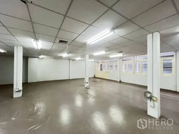 Shophouse for rent in Phra Khanong, Bangkok - Large upper-level workspace with fluorescent lighting and louvered windows.
