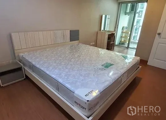 คอนโด ให้เช่าในHuai Khwang, Bangkok - ห้องนอนใหญ่ เตียงขนาดใหญ่ โต๊ะข้างเตียง และทางออกสู่ระเบียง