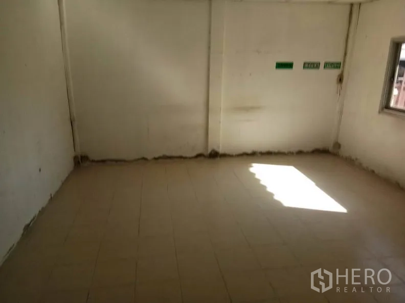 Warehouse for rent in Bang Sao Thong, Samut Prakan - Second office space with window, tiled flooring and clear exit signage.