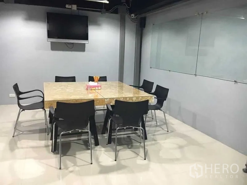联排别墅 出售在Wang Thonglang, Bangkok - 会议室，大理石桌、黑色椅子、壁挂电视与玻璃白板