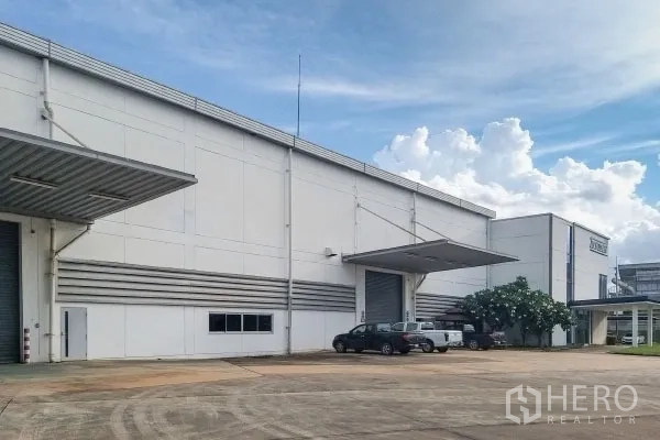 Factory for sale in Rayong - Factory frontage showing multiple docking bays, parking area and landscaped tree.