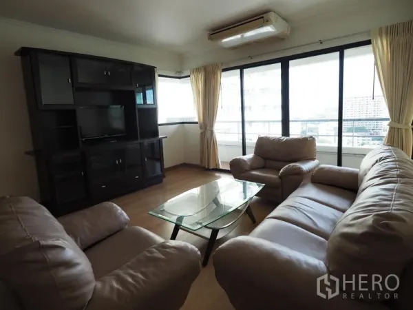 Condominium for rent in Sathon, Bangkok - Corner lounge with large windows, leather sofas, TV cabinet and city outlook from a Sathon condominium.