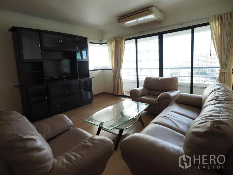 Condominium for rent in Sathon, Bangkok - Corner lounge with large windows, leather sofas, TV cabinet and city outlook from a Sathon condominium.