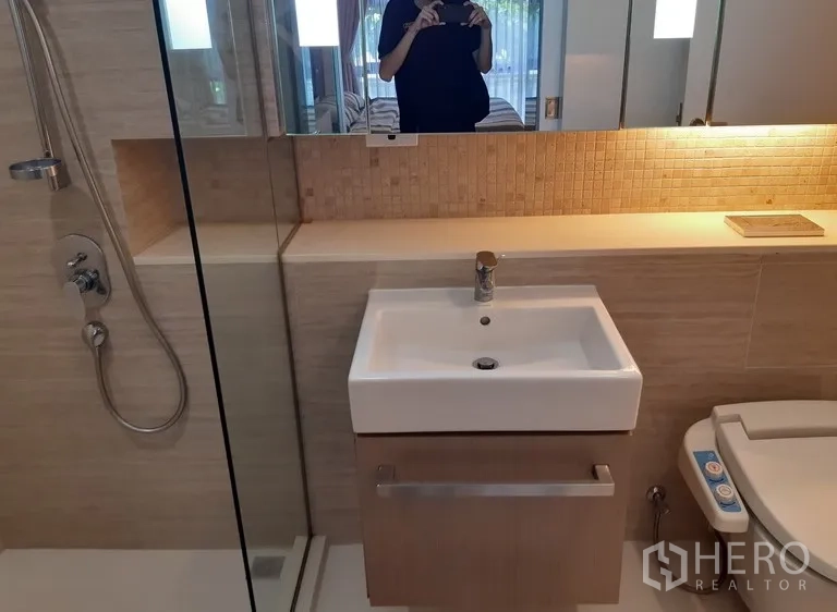 公寓 出租在Watthana, Bangkok - 浴室台盆与玻璃淋浴间，旁有智能洁身马桶座，色调素雅。