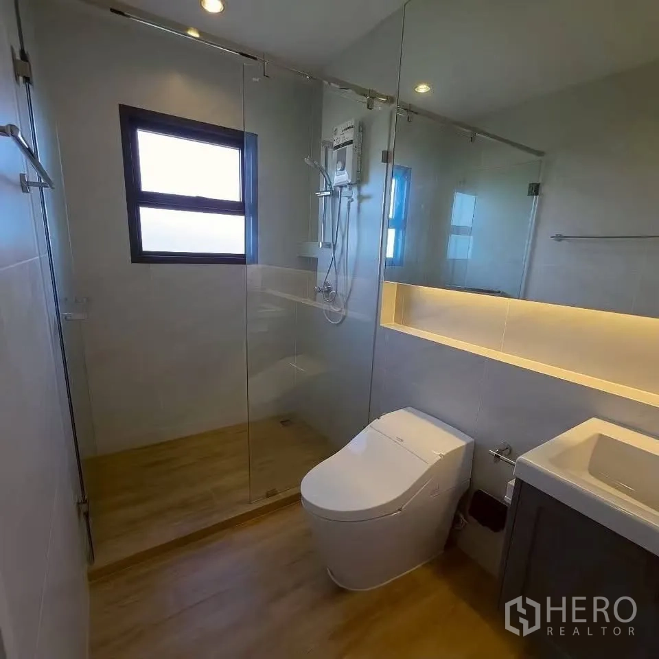 Detached House for rent in Bang Phli, Samut Prakan - Bathroom with glass shower enclosure, wall niche lighting, and vanity.