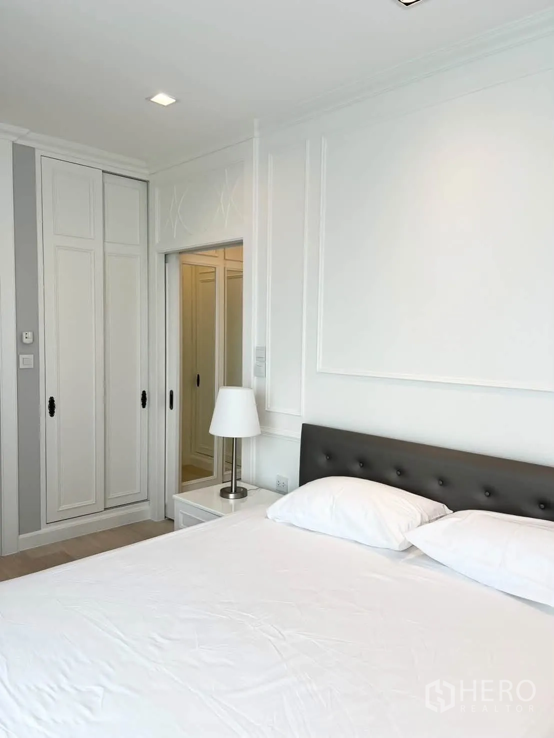 Condominium for rent in Pathum Wan, Bangkok - Bedroom with upholstered headboard, side table, and fitted wardrobes.