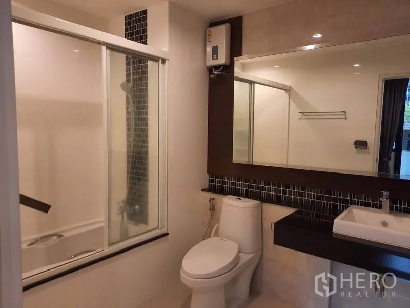 Condominium for rent in Watthana, Bangkok - Second bathroom featuring a bathtub with glass screen, mosaic backsplash, wide mirror and modern vanity.