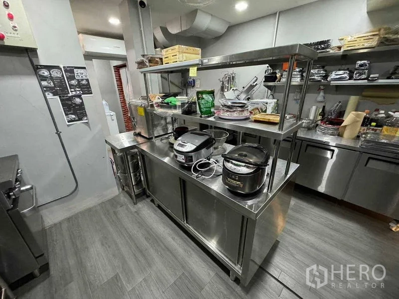 Shophouse for rent in Watthana, Bangkok - Stainless work island and storage in a compact commercial kitchen.