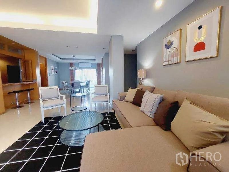 Apartment for rent - Cozy living room with sectional sofa, black grid rug, round glass coffee table, and framed artwork.