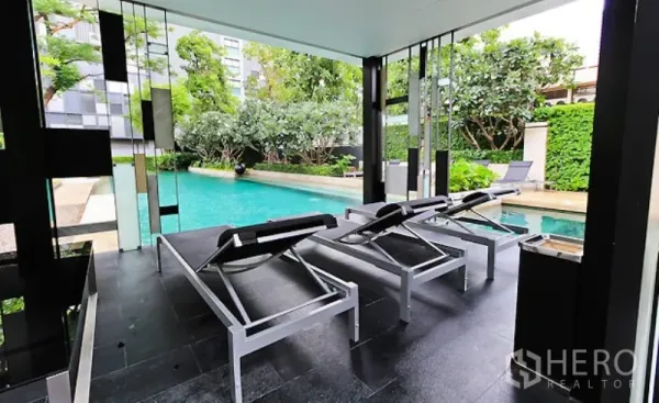 คอนโด ให้เช่าในWatthana, Bangkok - พื้นที่นั่งเล่นริมสระแบบมีหลังคา พร้อมเตียงอาบแดด มองเห็นสระและสวนสวยงาม