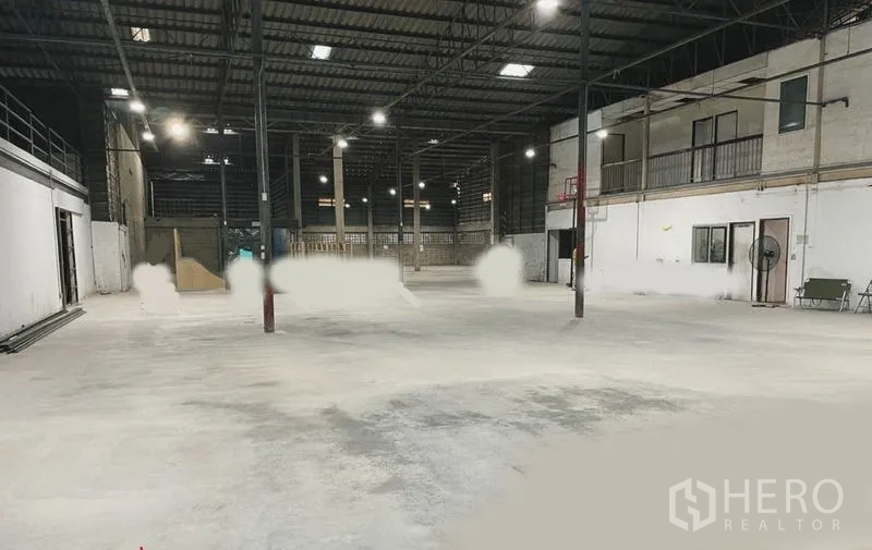 Warehouse for rent or sale in Mueang Nonthaburi, Nonthaburi - Spacious warehouse interior with high steel truss roof, concrete floor, and mezzanine offices along one wall.
