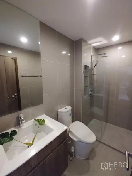 公寓 出租在Huai Khwang, Bangkok - 现代浴室，玻璃淋浴间、洗手台与浅色瓷砖。