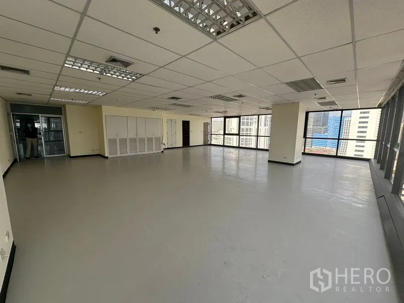 Office Space for rent in Bang Rak, Bangkok - Corner open-plan office with large windows, city skyline views, grid ceiling lighting and built-in storage cabinets.