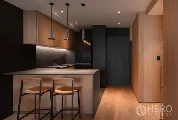 Condominium for rent in Phaya Thai, Bangkok - Sleek kitchen with island breakfast bar, two stools, wood cabinetry and dark accents.