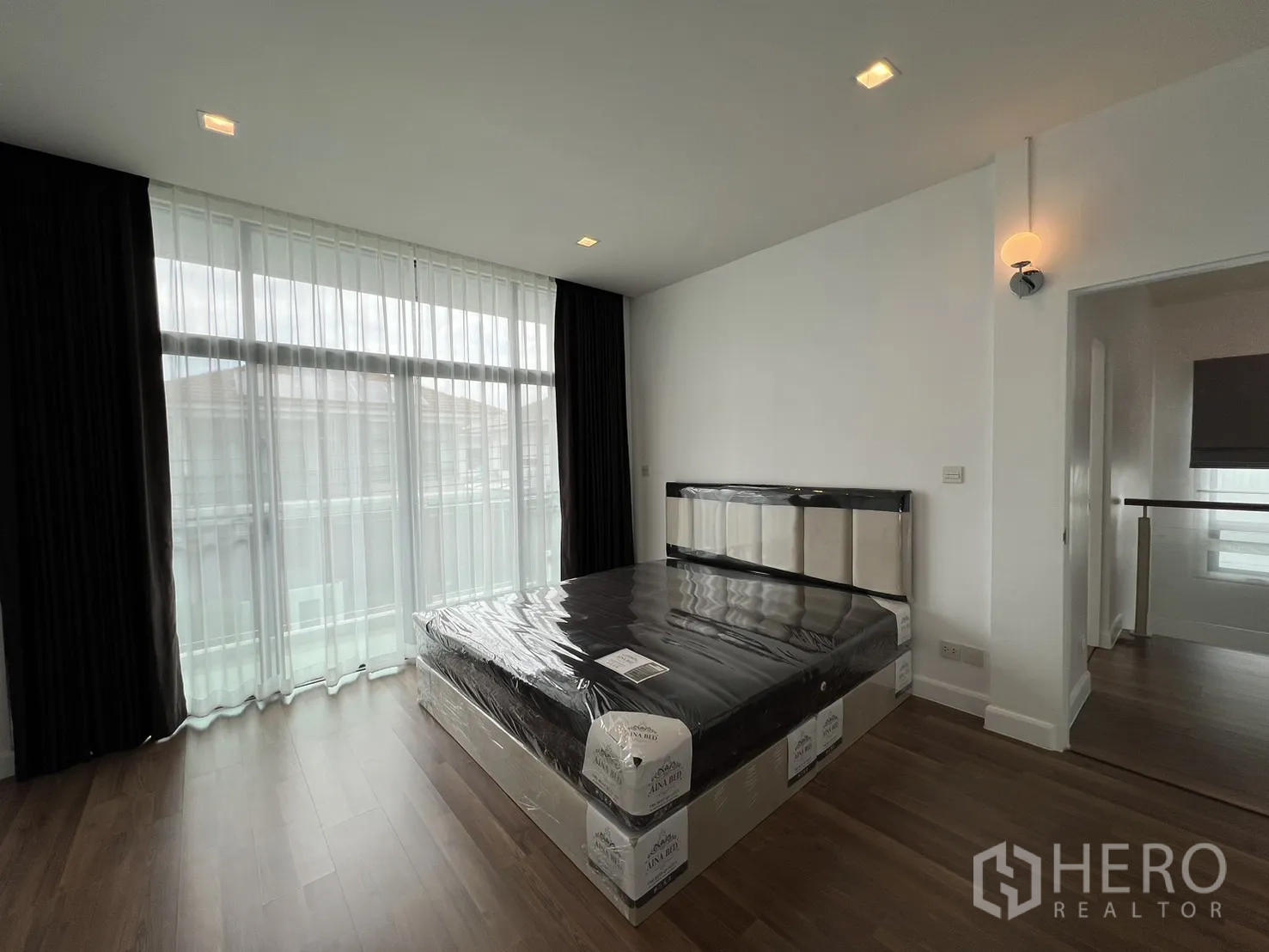 Detached House for rent in Bang Kapi, Bangkok - Master bedroom with large windows, wood floor and a new bed frame.