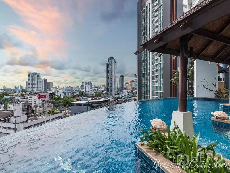 Condominium for rent in Watthana, Bangkok - Infinity‑edge swimming pool with city skyline backdrop and high‑rise buildings in Watthana.