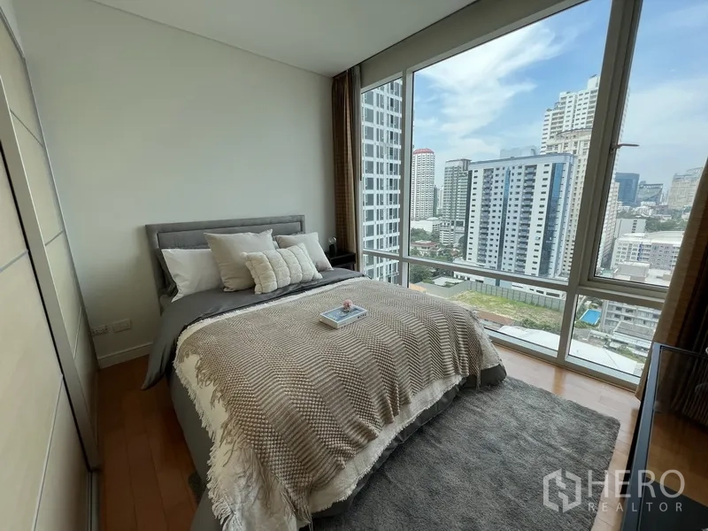 Condominium for rent in Watthana, Bangkok - Second bedroom with corner glass walls and skyline view.