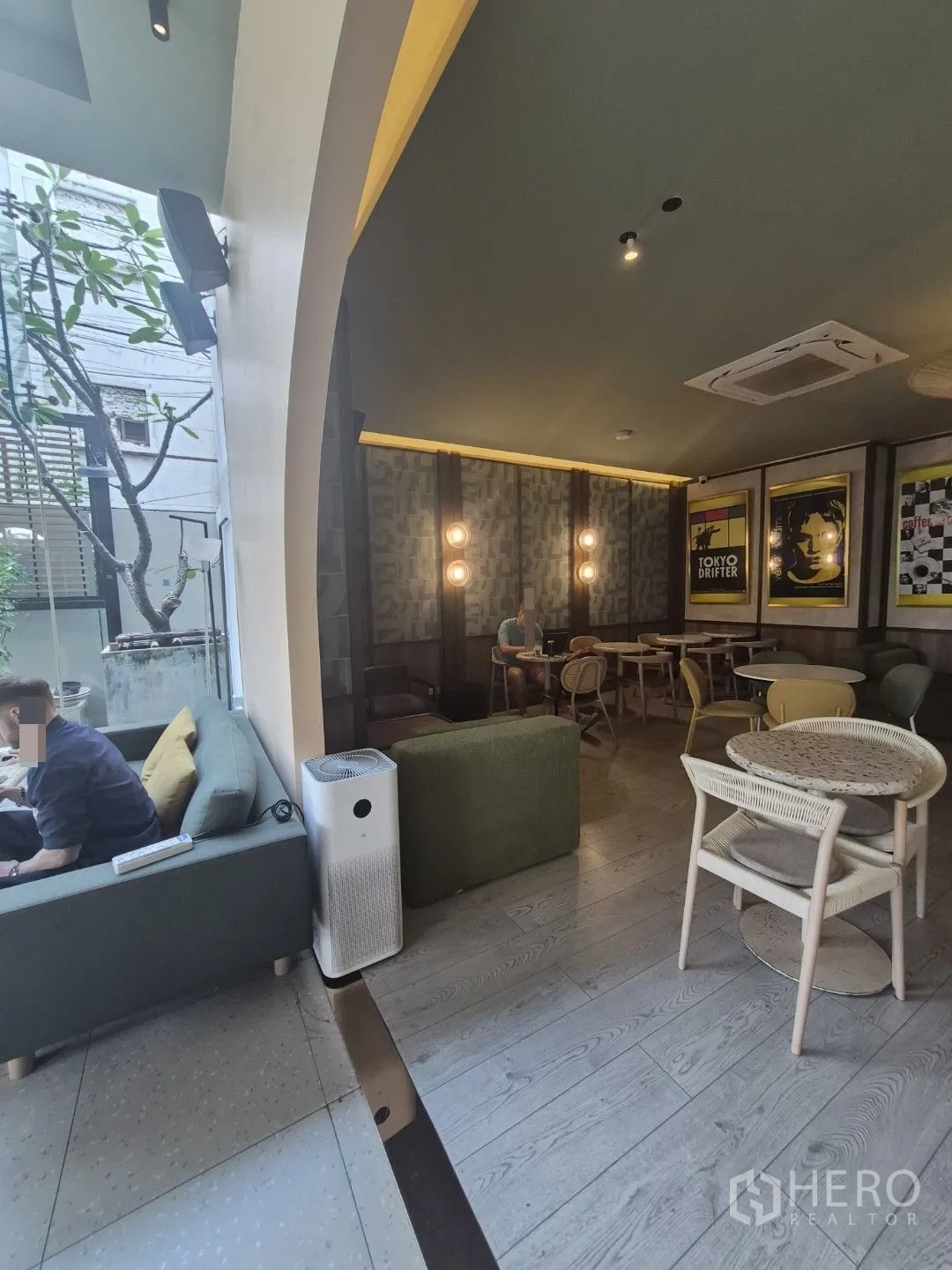 Retail Space for rent in Watthana, Bangkok - Cafe-style interior with sofas, round tables, wood flooring, and a large arched window.