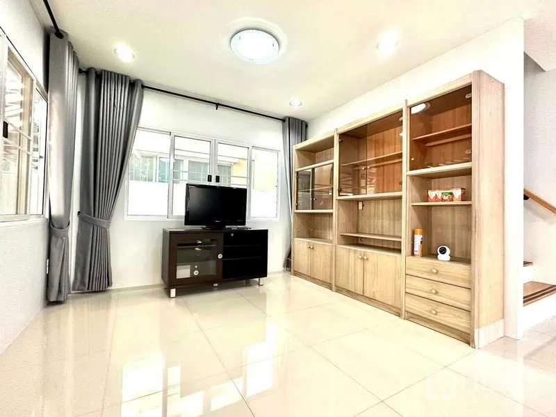 Detached House for rent in Lat Krabang, Bangkok - Living area with TV stand and large wood display cabinet beside windows.