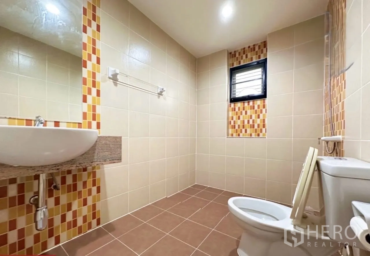 Detached House for sale in Lam Luk Ka, Pathum Thani - Bathroom with beige tiles, mosaic accents, wall-mounted sink and toilet.
