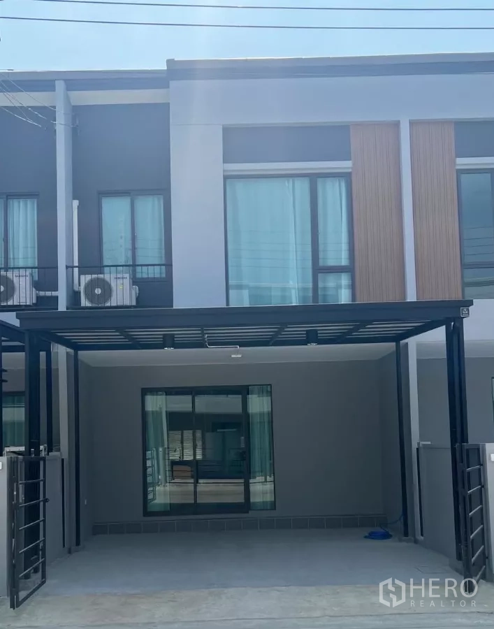 Townhouse for rent in Bang Phli, Samut Prakan - Modern two-storey townhouse facade with covered 2-car carport and large sliding glass doors.