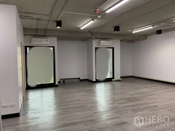 สำนักงาน ให้เช่า - พื้นที่ทำงานกว้าง เพดานเปลือย ไฟ LED หลายจุด และหน้าต่างสูงพร้อมเครื่องปรับอากาศ