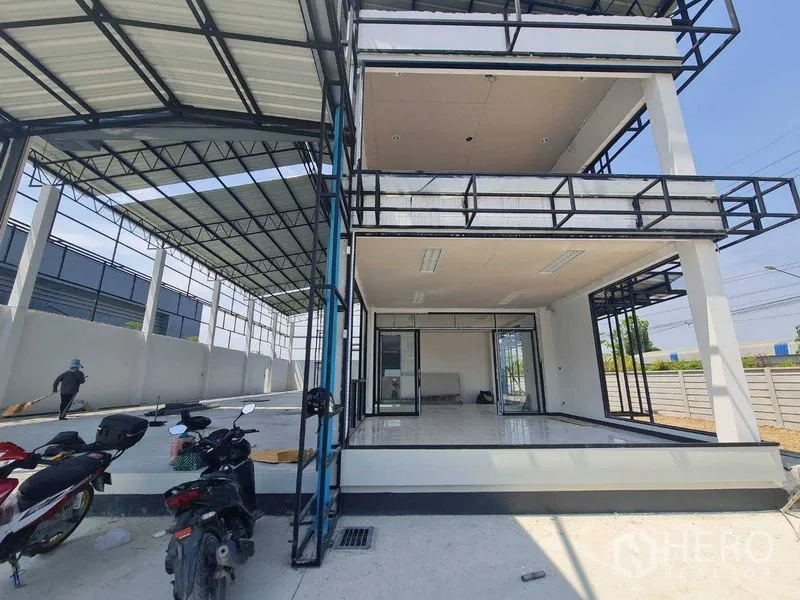 Warehouse for rent in Bang Len, Nakhon Pathom - Open-plan office and mezzanine levels with sliding glass doors next to a sheltered work bay in the warehouse.