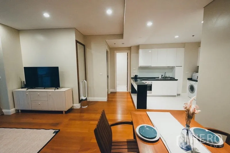 Condominium for rent in Khlong Toei, Bangkok - View from dining to white kitchen with cabinets and wood floors.
