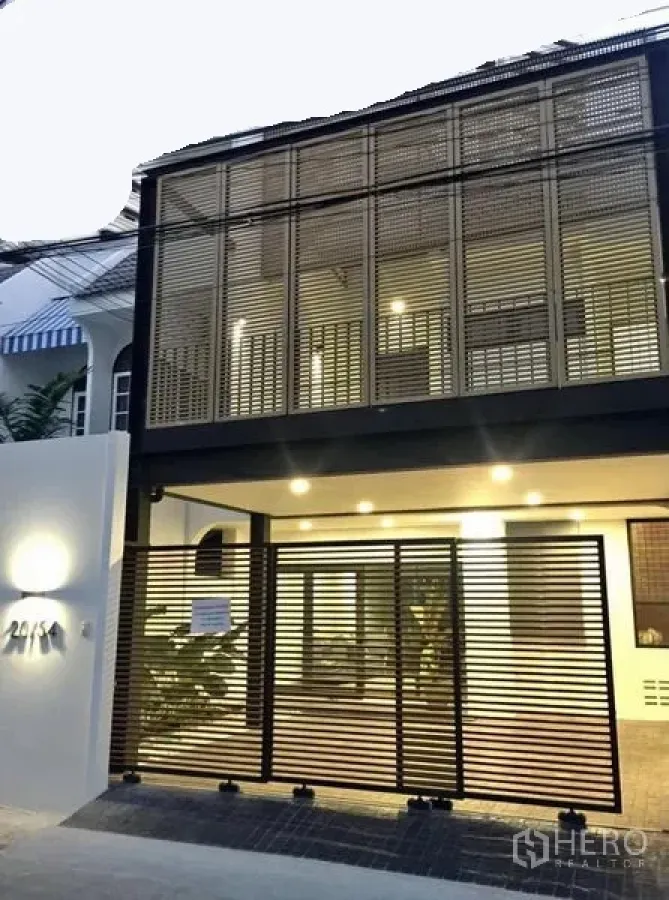 联排别墅 出租在Khlong Toei, Bangkok - 现代两层联排别墅外立面，格栅遮阳，带门控车位与暖色照明