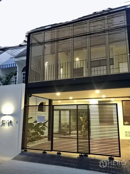 联排别墅 出租在Khlong Toei, Bangkok - 现代两层联排别墅外立面，格栅遮阳，带门控车位与暖色照明