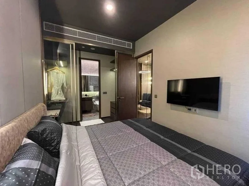 Condominium for rent in Khlong Toei, Bangkok - Bedroom showing the bed, wall‑mounted TV and doorway to the dressing area and bathroom.