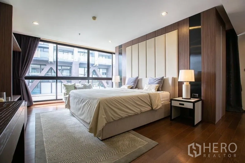 Condominium for rent or sale - Primary bedroom with padded headboard, large picture windows and wood floors.