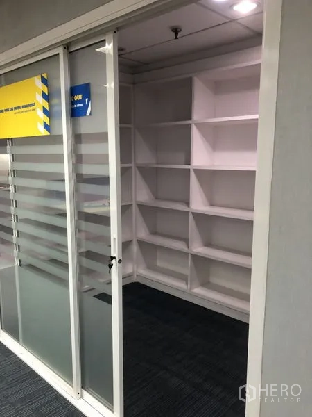 Office Space for rent - Storage room with built-in white shelving behind a sliding frosted glass door.