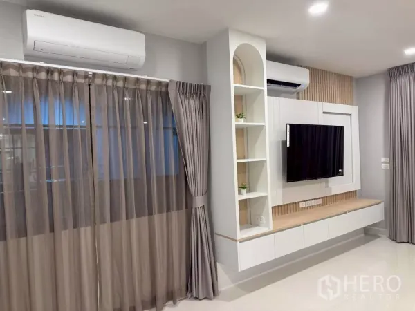 บ้าน ให้เช่าในBang Phli, Samut Prakan - พื้นที่พักผ่อนสว่างด้วยผนังทีวี ตู้ลอย ชั้นวาง หน้าต่างบานใหญ่ และแอร์