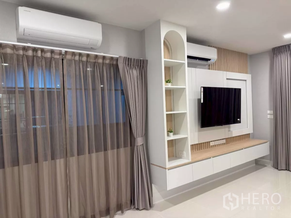 บ้าน ให้เช่าในBang Phli, Samut Prakan - พื้นที่พักผ่อนสว่างด้วยผนังทีวี ตู้ลอย ชั้นวาง หน้าต่างบานใหญ่ และแอร์