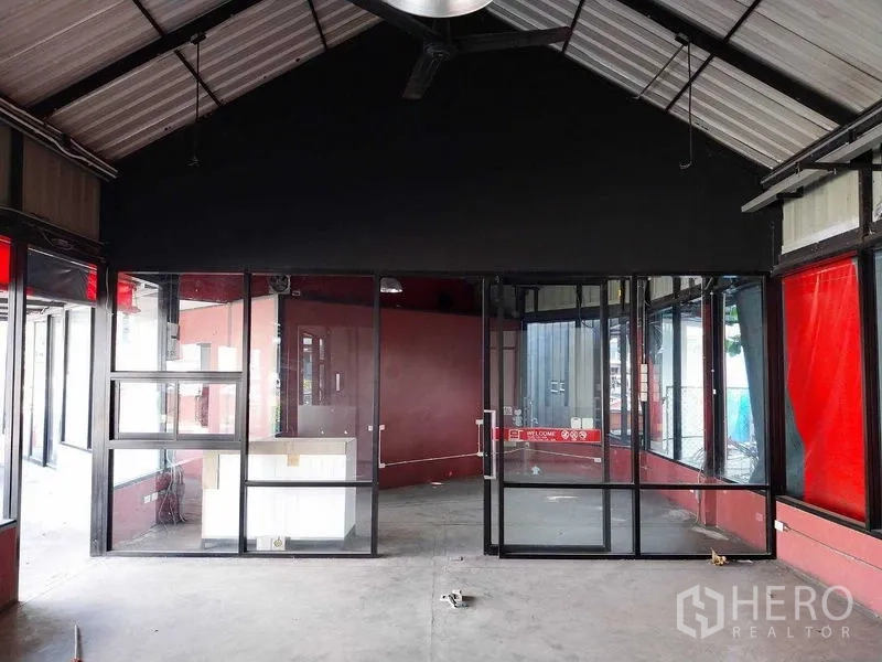 Retail Space for rent in Khlong Toei, Bangkok - Open-plan retail space featuring glass entrance doors, red accent walls, and wraparound display windows.