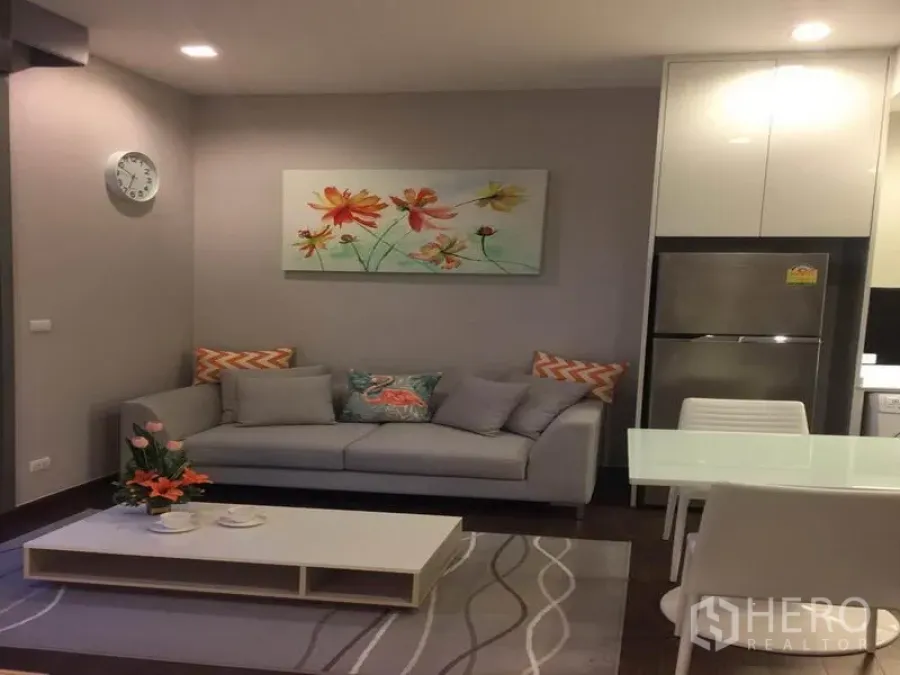 公寓 出租在Ratchathewi, Bangkok - 温馨客厅，灰色沙发、茶几与餐桌，嵌灯照明柔和。