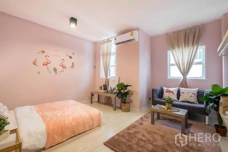 Detached House for rent in Khlong Toei, Bangkok - Pastel pink bedroom with bed, compact sofa, air-conditioner and two windows.