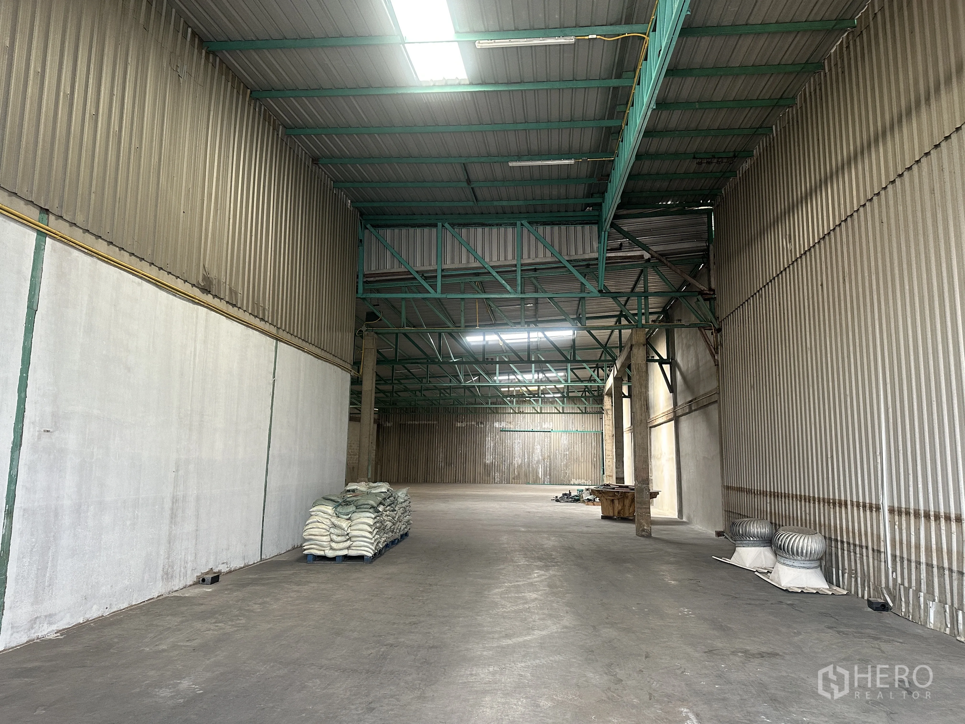 货栈 出租在Mueang Pathum Thani, Pathum Thani - 仓库纵深视角，通透的清空区域，屋面通风器与荧光灯照明。