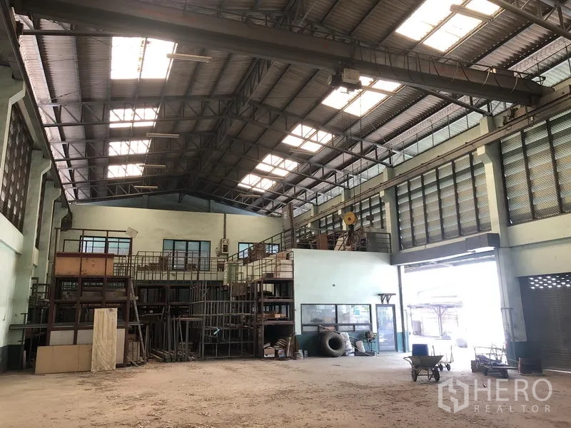 Warehouse for rent or sale in Lam Luk Ka, Pathum Thani - Main warehouse hall featuring an overhead crane beam and wide shutter opening.