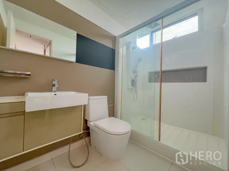 Condominium for sale - Bathroom featuring glass-enclosed shower, vanity and toilet.