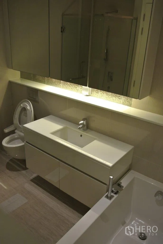 Condominium for rent in Watthana, Bangkok - Modern bathroom with wide vanity, bathtub, toilet and mirrored cabinetry.