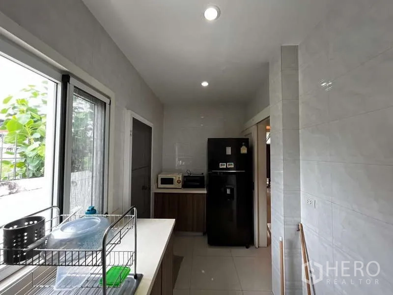独立式住宅 出租在Prawet, Bangkok - 实用走廊式厨房，带窗、冰箱与储物柜。