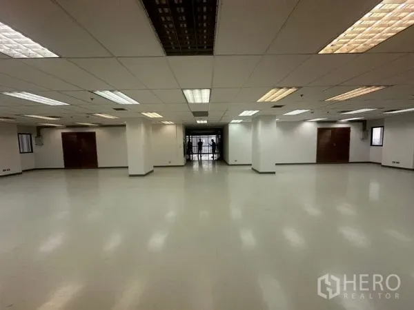 办公空间 出租在Phaya Thai, Bangkok - 宽敞空置办公室，吊顶荧光灯、白色立柱、光滑地面与尽头的玻璃入口。