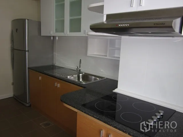 Condominium for rent or sale in Watthana, Bangkok - Close-up of modern kitchen showing electric cooktop, range hood, and stainless sink.