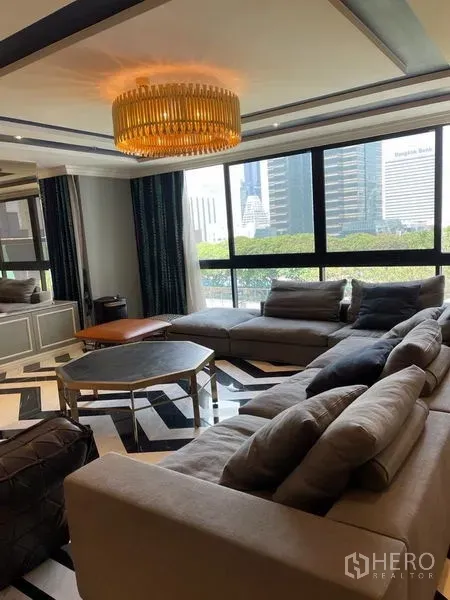 公寓 出租或出售在Sathon, Bangkok - 萨通公寓客厅，转角沙发与吊灯，大窗户享城市景观。