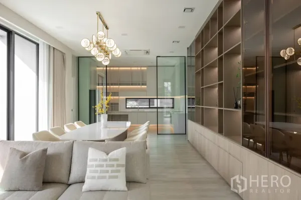 Detached House for rent in Saphan Sung, Bangkok - Bright open-plan dining and living area with glass-partitioned kitchen and full-height shelving.